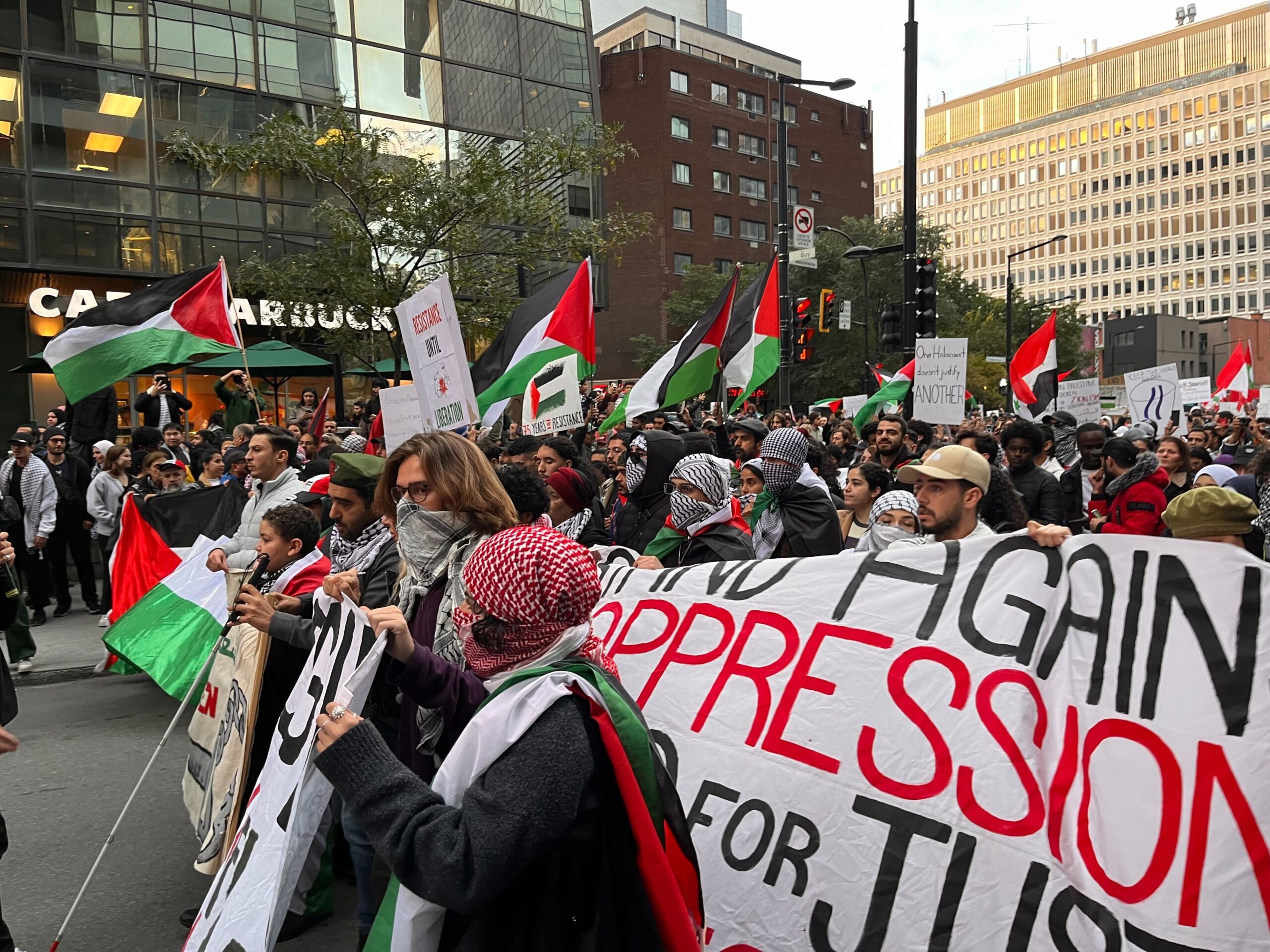 Protestors holding banners and Palestinian flags march on downtown Montreal streets.